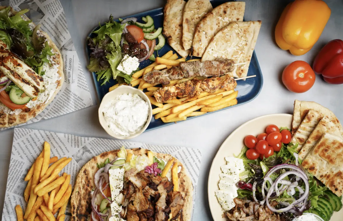 Græsk pita, mezze, tzatziki og pommes frites serveret på bakker
