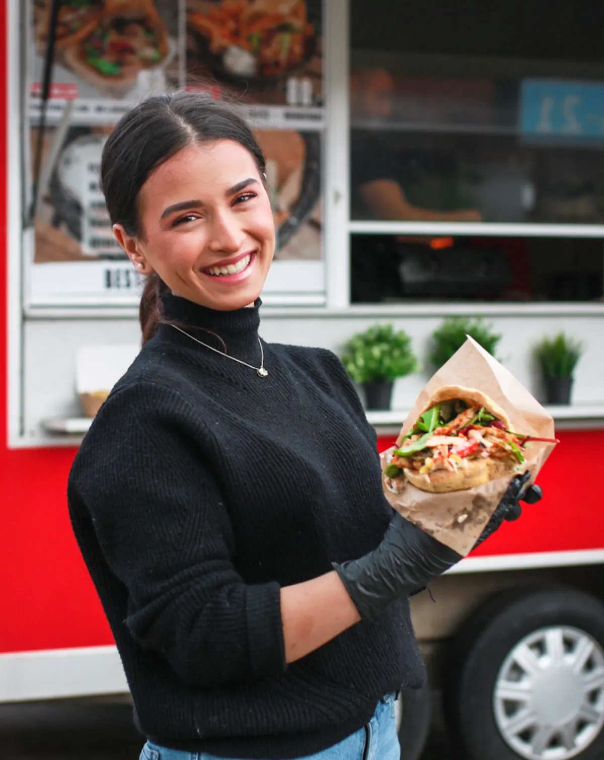 Medarbejder fra Just Pita viser en frisk pita foran pita foodtrucken